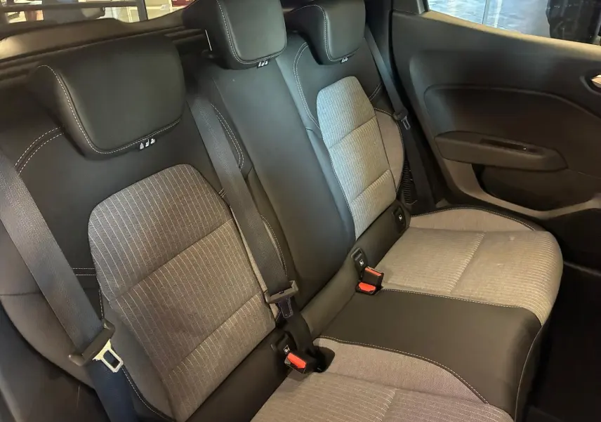 Vue intérieure arrière de la Renault Clio V E-TECH 145 TECHNO 2025, sièges tissu gris et noir avec surpiqûres blanches.
