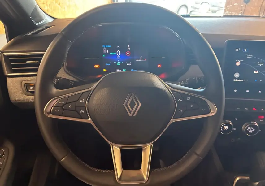 Vue centrée sur le volant noir de la Renault Clio V E-TECH 145 TECHNO 2025 avec tableau de bord numérique et écran tactile.
