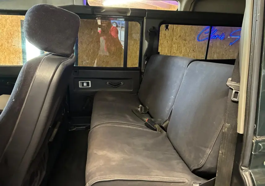 Vue intérieure côté droit du Land Rover Defender 110 2.5 TD 122 4x4 2005, sièges arrière en tissu noir.