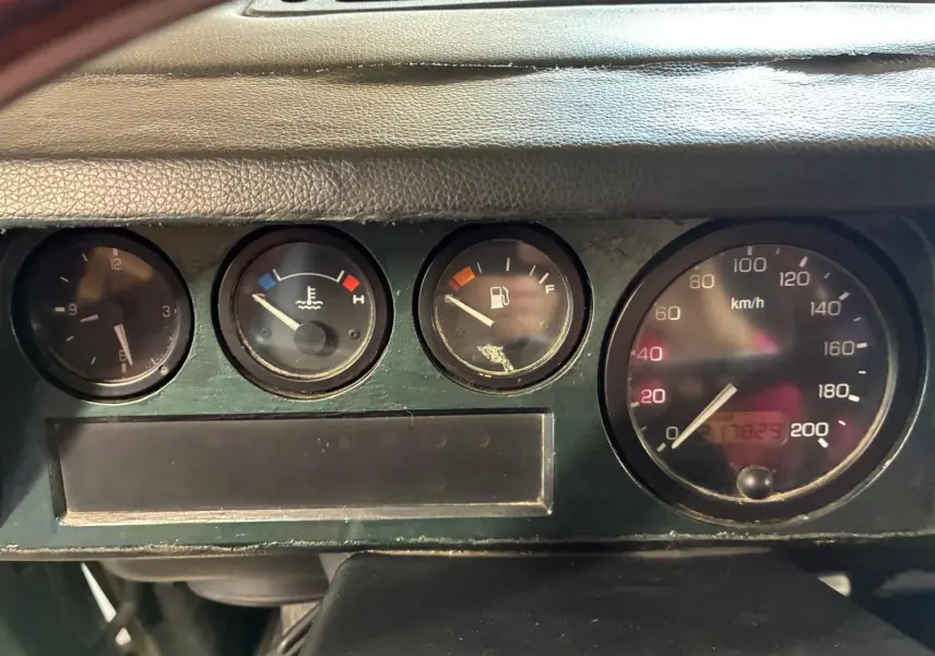 Gros plan sur le tableau de bord vert foncé du Land Rover Defender 110 2005, montrant les compteurs ronds et le compteur de vitesse.