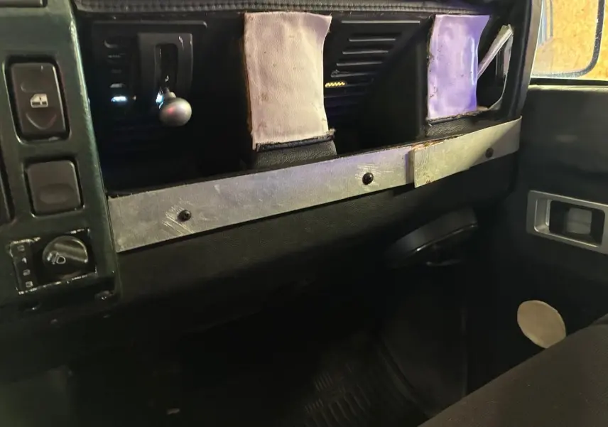 Vue intérieure du tableau de bord du Land Rover Defender 110 vert 2005, mettant en valeur la console centrale et les commandes.