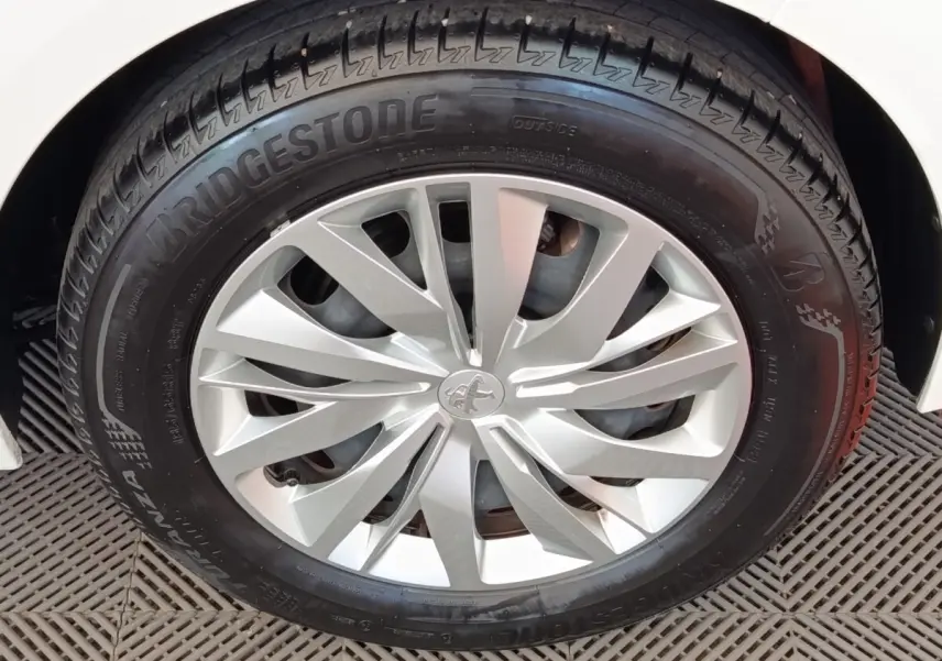 Gros plan sur la roue avant droite d'une Peugeot 208 blanche, mettant en valeur la jante argentée au design moderne.