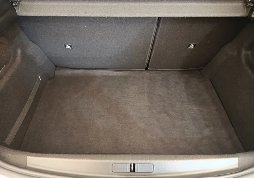Coffre vide vu de face d'une Peugeot 208 blanche BlueHDi 100 S&S Active, intérieur en moquette grise.