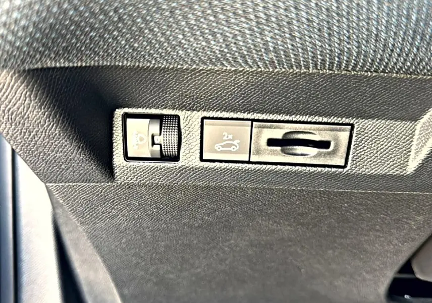 Gros plan sur les commandes d'ouverture du coffre et réglage des phares dans l'habitacle du Citroën C5 Aircross gris platinium.