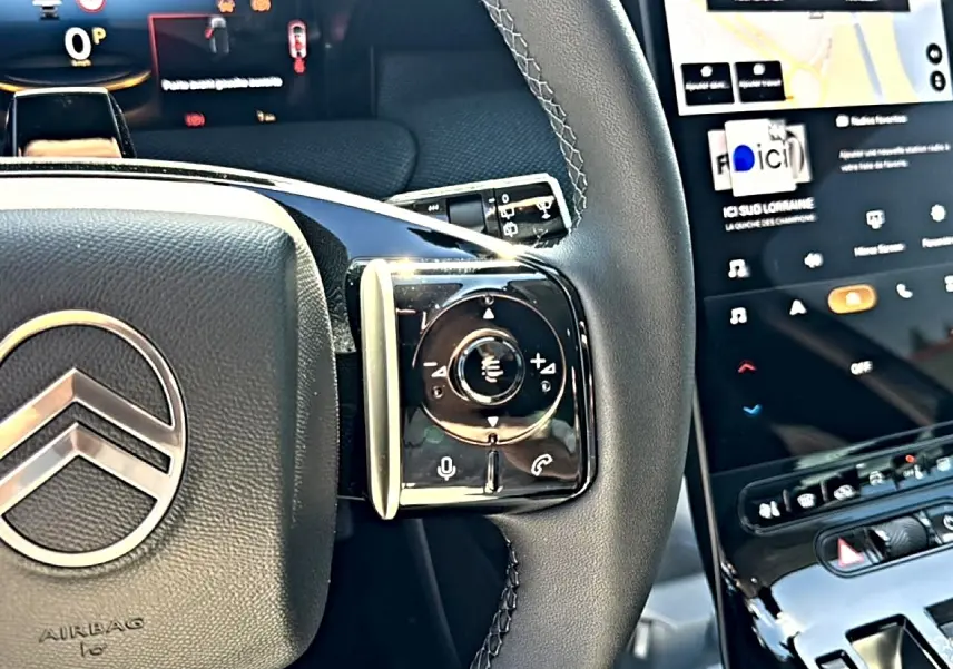 Gros plan sur le volant cuir noir et les commandes multifonctions du Citroën C5 Aircross 2026, écran tactile visible.