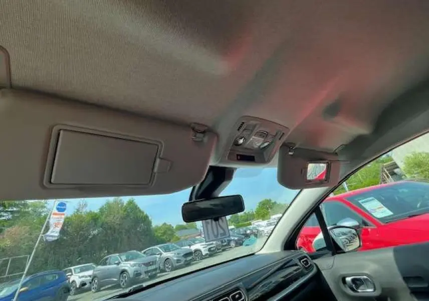 Vue intérieure avant de la Citroën C3 2023 noire métal, montrant tableau de bord et pare-soleil ouverts.
