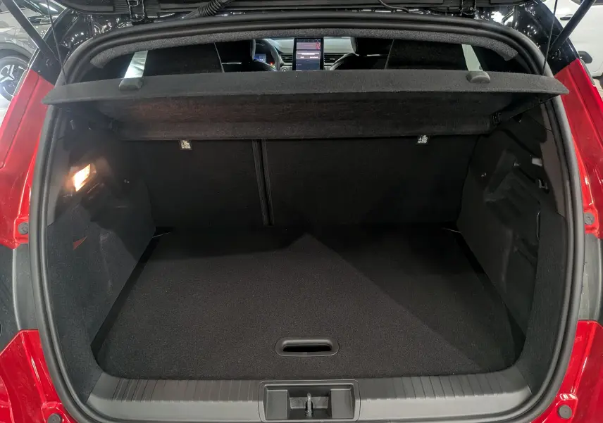 Coffre ouvert vu de l'arrière d'un Renault Captur E-Tech rouge flamme avec toit noir, intérieur noir et tablette de coffre relevée.