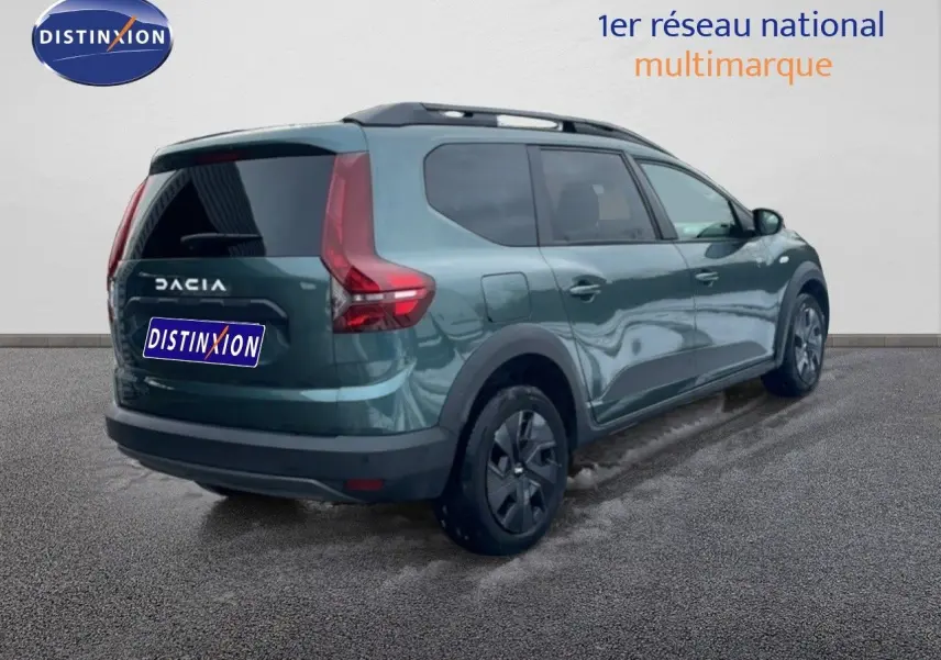 Vue 3/4 arrière droite d'un Dacia Jogger 2025 vert cèdre métallisé avec vitres teintées et barres de toit.