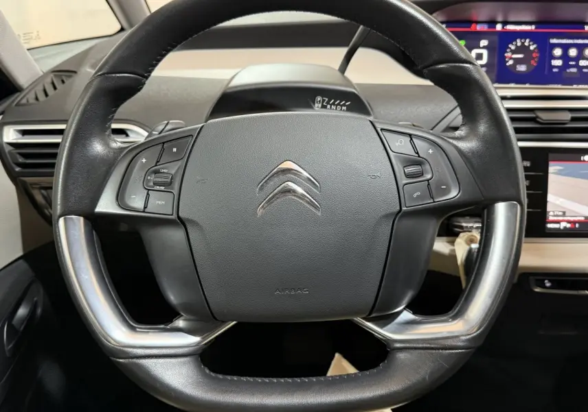 Vue rapprochée du volant cuir et alu noir du Citroën C4 Spacetourer 2020 avec tableau de bord numérique en arrière-plan.