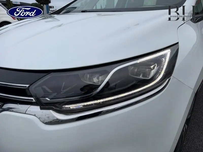 Gros plan sur le phare avant droit blanc glacier du Renault Espace 2015 avec signature lumineuse LED distinctive.