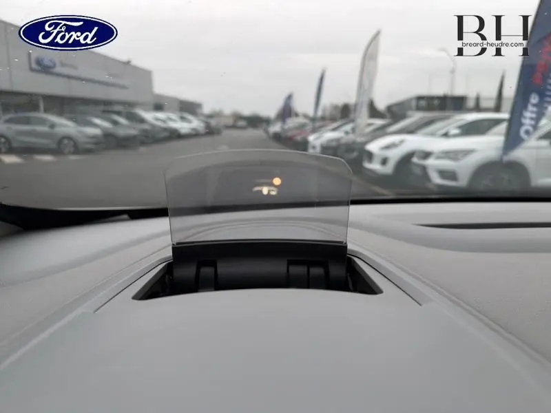 Affichage tête haute en fonctionnement sur tableau de bord gris clair, vue depuis l'intérieur vers l'extérieur.