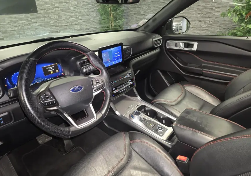 Vue intérieure côté conducteur du Ford Explorer 2020, sièges cuir noirs avec surpiqûres rouges et écran tactile central.