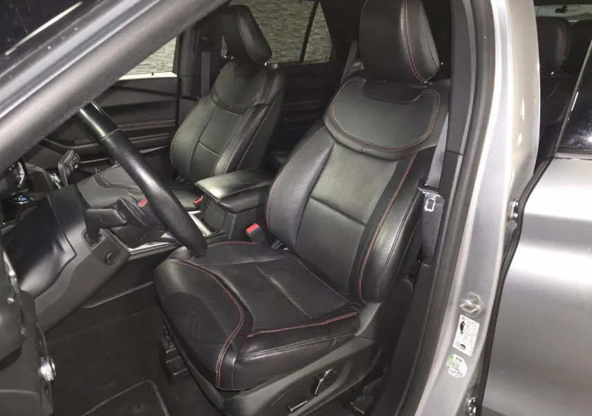 Vue intérieure côté conducteur du Ford Explorer gris, sièges cuir noirs avec surpiqûres rouges et volant sport ST-Line.