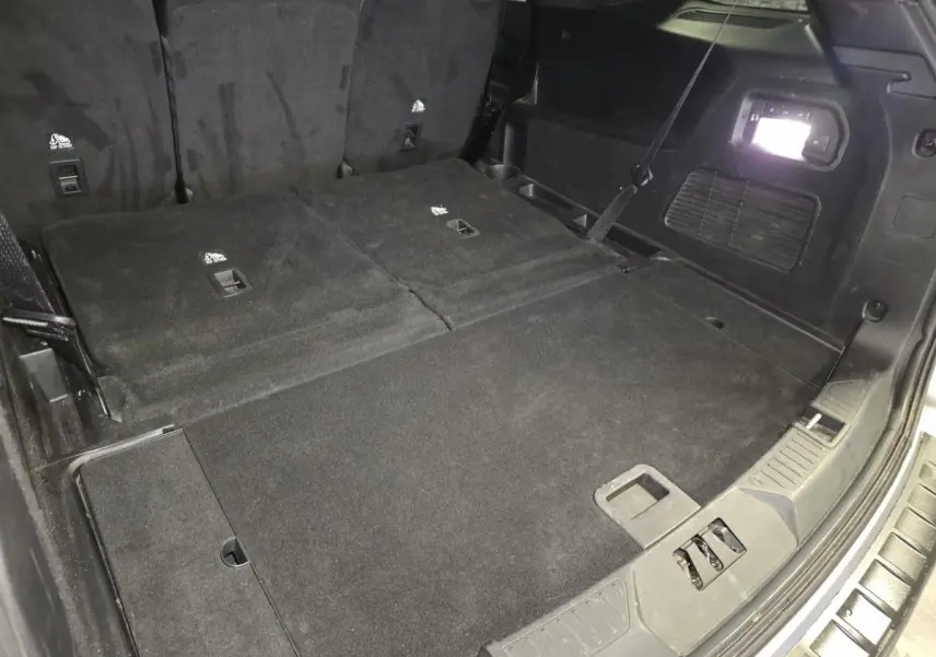 Vue du coffre arrière avec banquette rabattue du Ford Explorer gris, mettant en valeur l'espace de chargement plat.