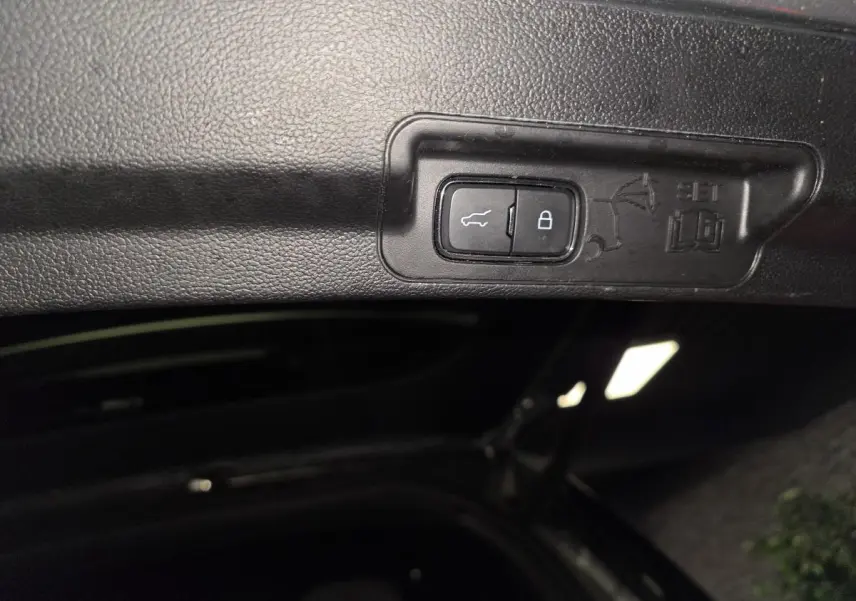 Bouton d'ouverture et de verrouillage électrique du coffre sur le hayon intérieur du Ford Explorer gris.