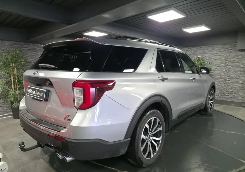 Vue 3/4 arrière droite du Ford Explorer gris métallisé avec attelage et jantes alliage noires brillantes.
