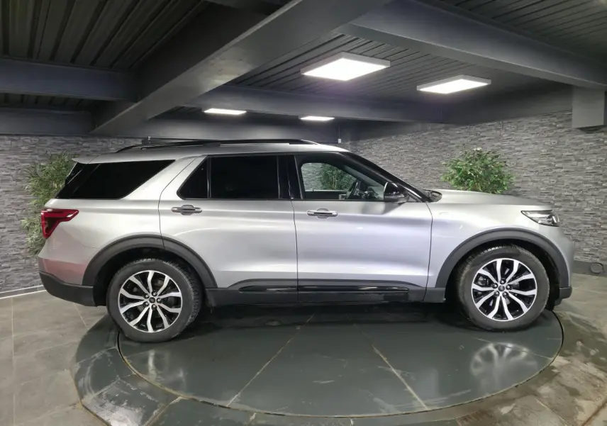 Ford Explorer gris métallisé vu de profil côté gauche dans un garage, avec jantes alliage noires et toit noir.