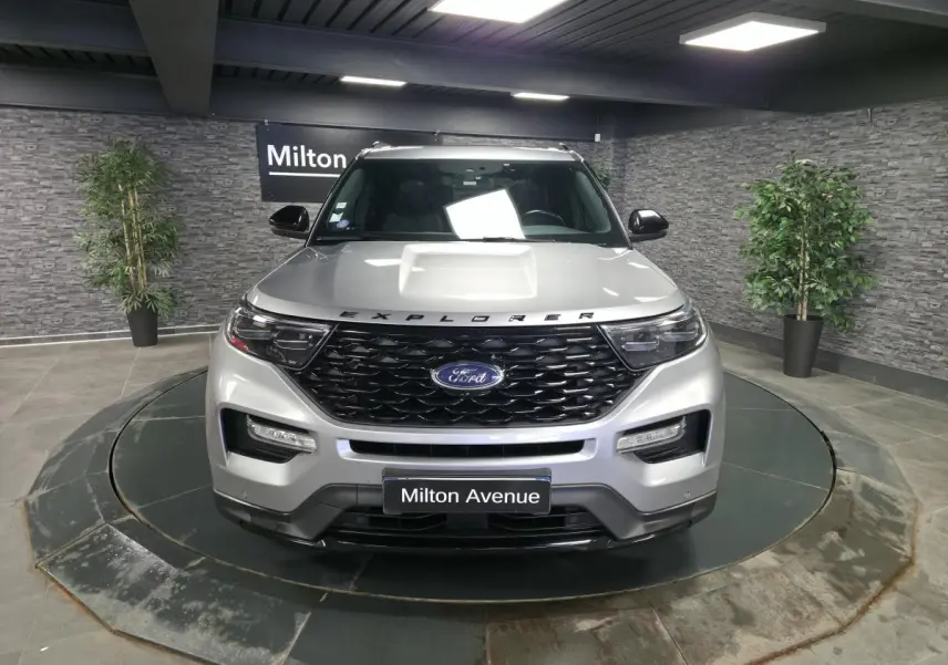 Vue avant d'un Ford Explorer gris métallisé avec calandre noire brillante et inscription Explorer sur le capot.