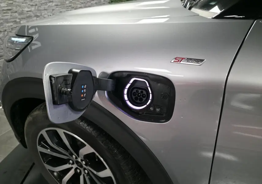 Prise de recharge ouverte côté avant gauche du Ford Explorer gris métallisé ST-Line avec jante alliage noire et badge ST-Line.