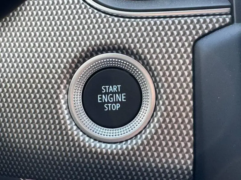 Gros plan sur le bouton Start Engine Stop entouré d'une finition texturée gris métal dans l'habitacle du Renault Arkana noir.