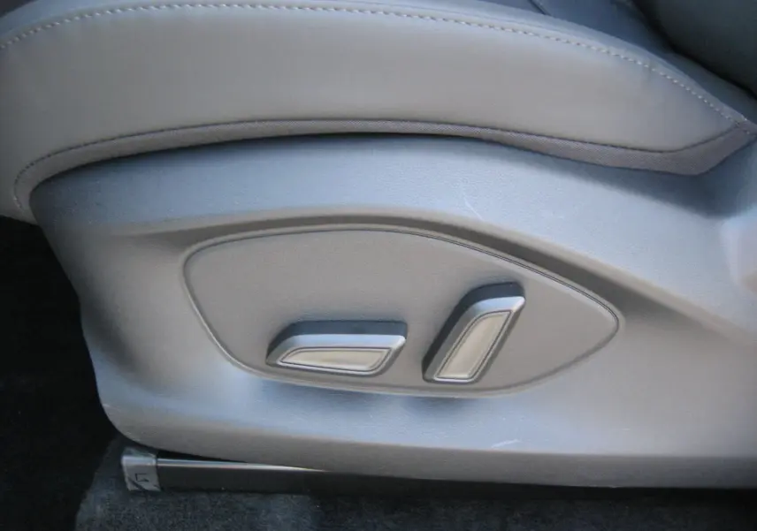 Détail des commandes de réglage électrique du siège en cuir noir du MG ZS 1.5 HYBRID+197 LUXURY blanc, vue côté gauche.