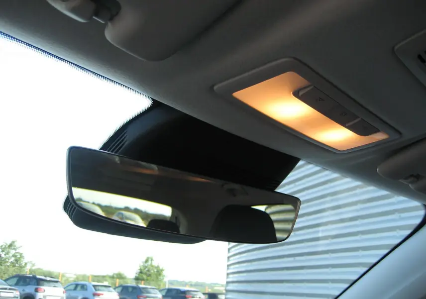 Vue intérieure du rétroviseur central d'un MG ZS blanc, avec plafonnier allumé et reflet de véhicules à l'arrière.