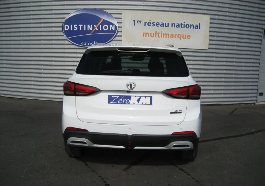 Vue arrière d’un MG ZS blanc 2026 avec feux rouges, logo MG central et plaque « Zero KM » visible.
