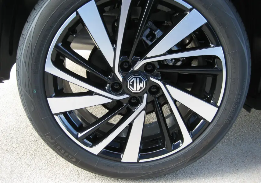 Gros plan sur la jante noire et argentée du MG ZS blanc, mettant en valeur le logo MG au centre.