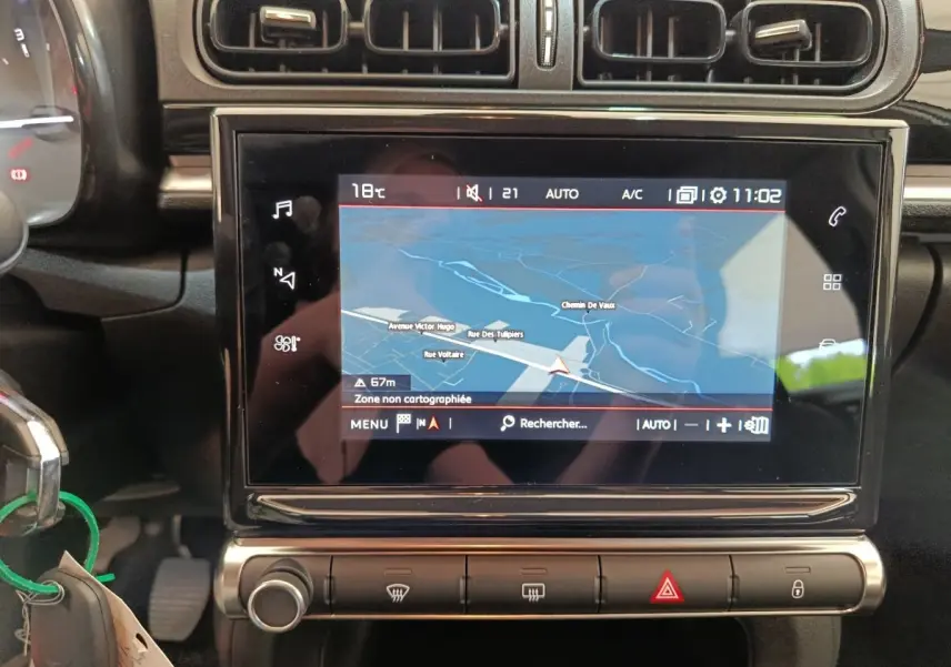 Vue rapprochée de l’écran tactile central du système de navigation 3D dans l’habitacle noir d’une Citroën C3 blanche.