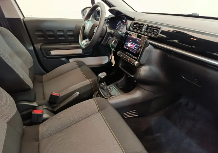 Vue intérieure côté conducteur de la Citroën C3 2022 avec tableau de bord noir, écran tactile et sièges gris.
