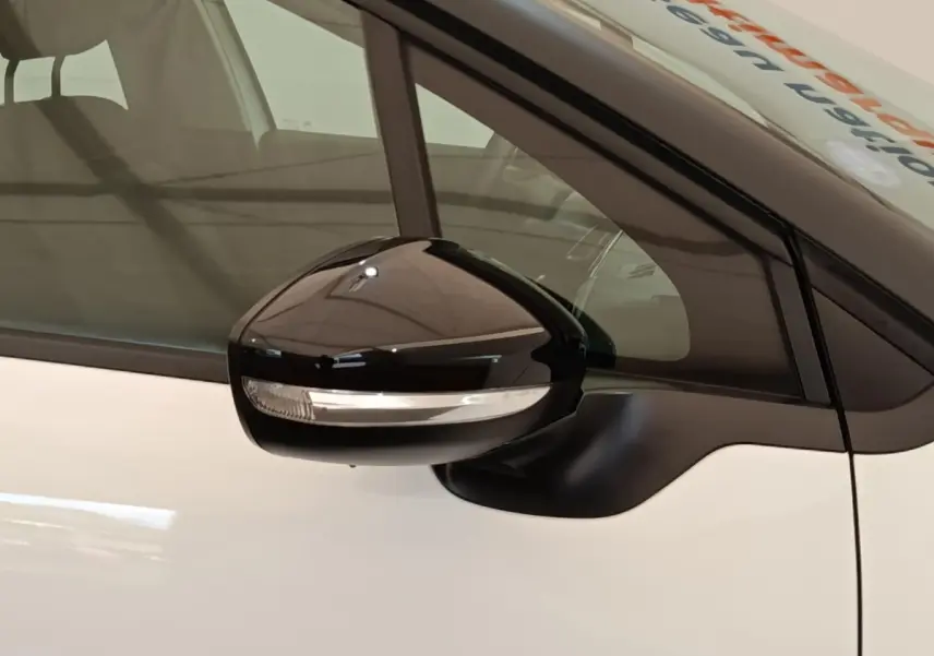 Rétroviseur noir avec clignotant intégré côté conducteur d'une Citroën C3 blanche, vue rapprochée.