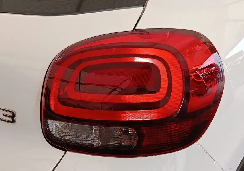 Gros plan sur le feu arrière droit rouge d'une Citroën C3 blanche, mettant en valeur son design arrondi et moderne.