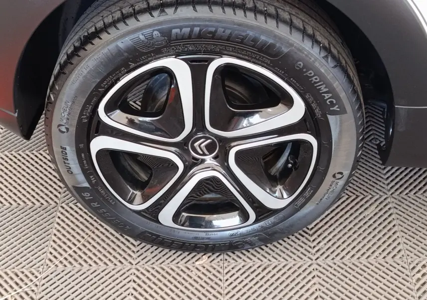 Gros plan sur la roue avant droite d'une Citroën C3 blanche, mettant en valeur la jante noire et argentée au design moderne.