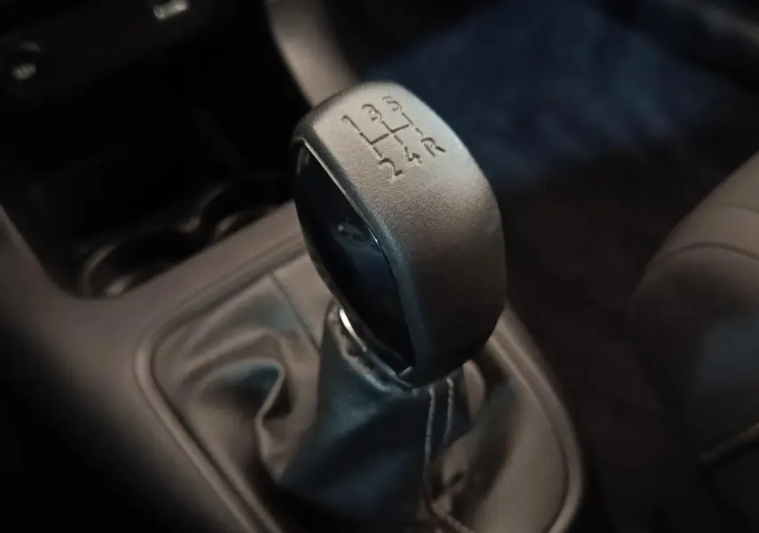 Gros plan sur le levier de vitesses manuel noir de la Citroën C3 blanche, avec indication des 5 rapports et marche arrière.