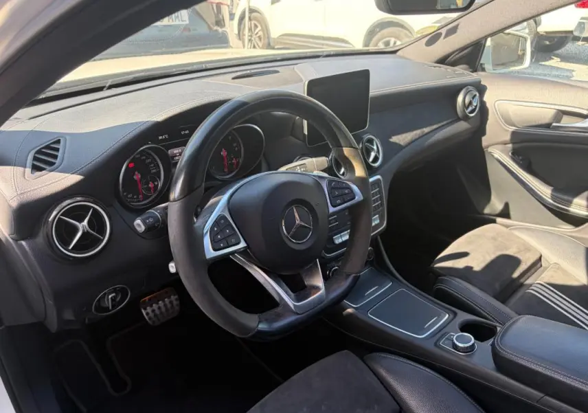 Vue intérieure côté conducteur du Mercedes GLA 220d White Art Edition 2017, tableau de bord noir avec volant multifonction et écran central.