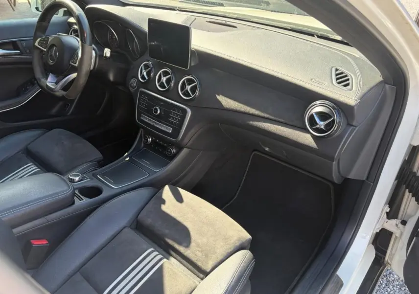 Vue intérieure côté passager du Mercedes GLA 220d blanc 2017, avec tableau de bord noir et aérateurs ronds chromés.