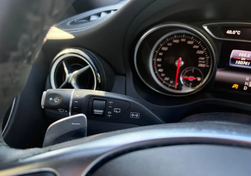 Gros plan sur le combiné d'instruments et la commande d'essuie-glace côté gauche du tableau de bord du Mercedes GLA blanc 2017.