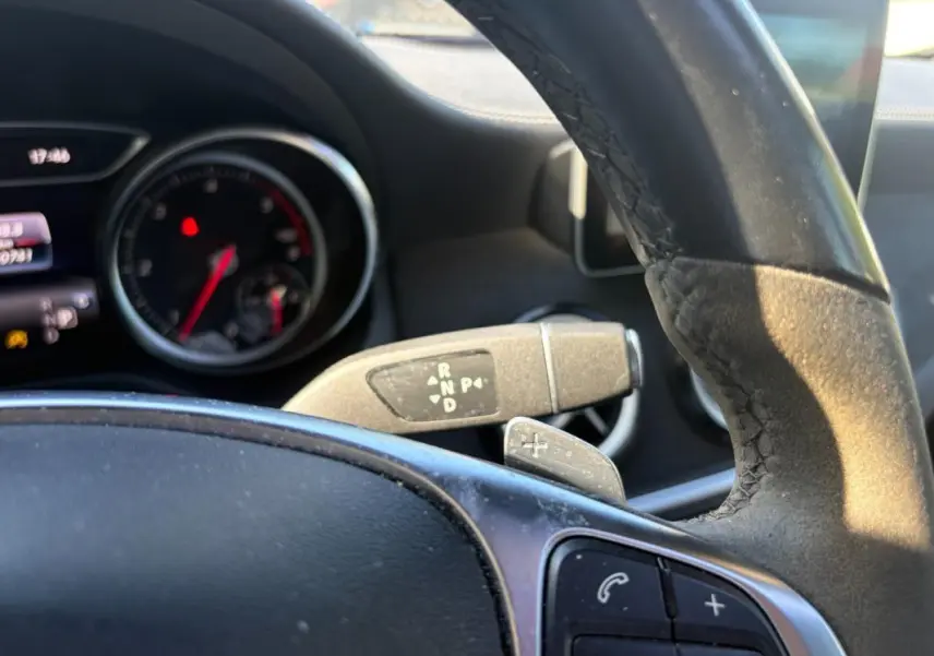 Vue intérieure rapprochée du volant et du levier de vitesses automatique d’un Mercedes GLA 220d blanc de 2017.