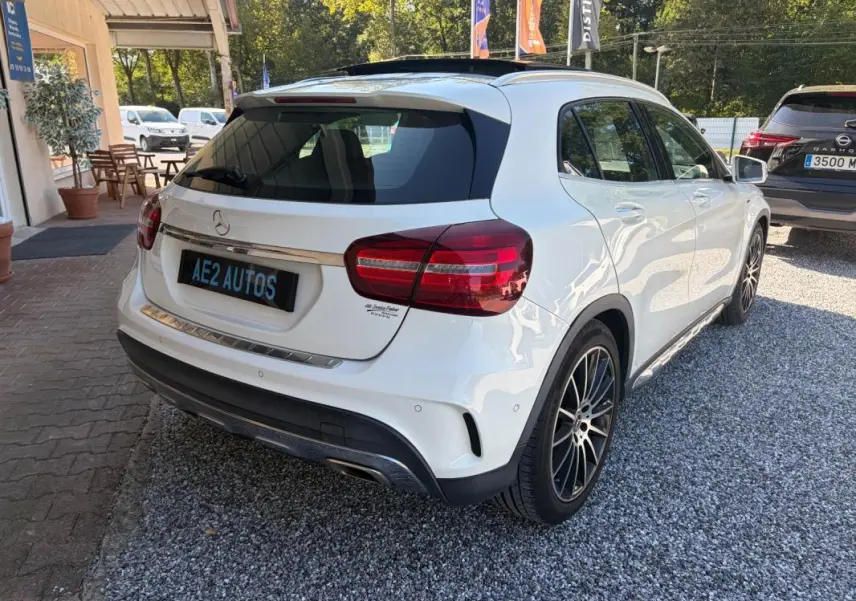 Vue 3/4 arrière droite d'une Mercedes GLA 220d blanche, avec jantes noires et détails chromés sur le hayon.