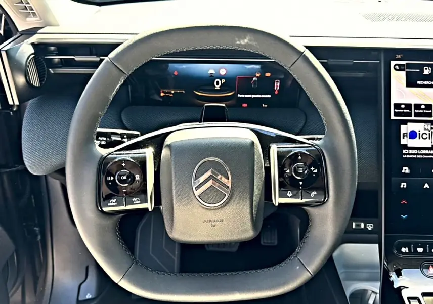 Vue rapprochée du volant multifonction noir du Citroën C5 Aircross 2026 avec tableau de bord numérique en arrière-plan.