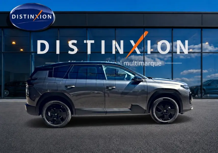 Profil droit du Citroën C5 Aircross gris platinium avec toit noir et jantes alliage noires devant une vitrine Distinxion.