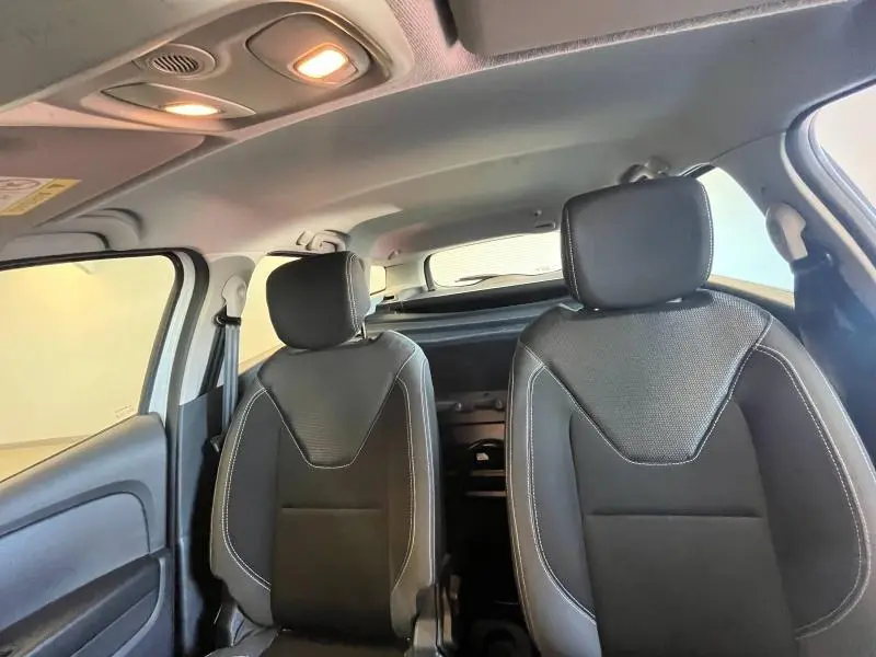 Vue intérieure avant de la Renault Clio Estate blanc glacier, sièges tissu noir avec surpiqûres blanches et plafonnier allumé.