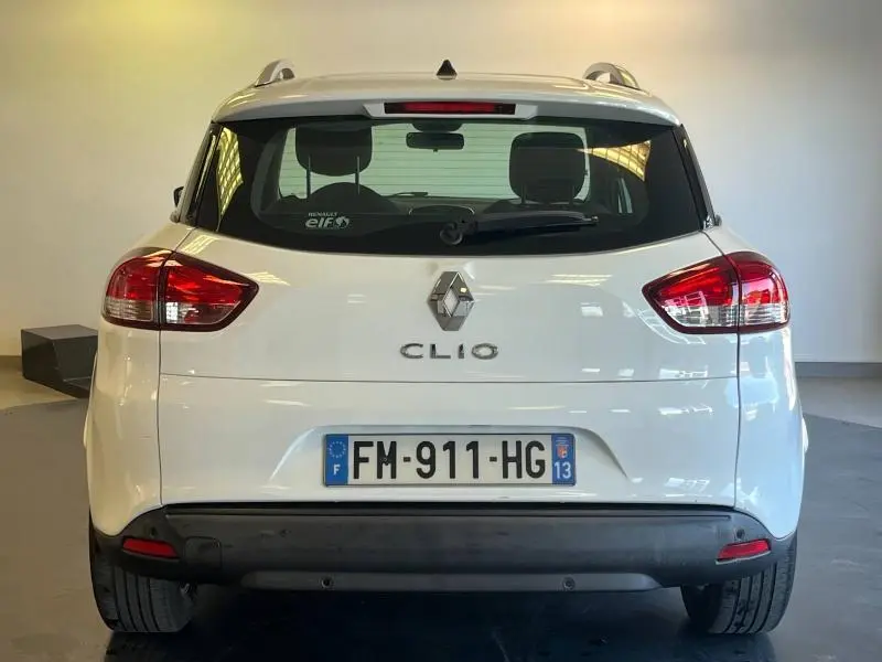 Vue arrière d'une Renault Clio Estate blanche Glacier avec feux arrière rouges et barres de toit visibles.