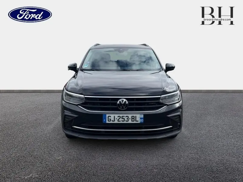 Vue avant d'un Volkswagen Tiguan 1.4 eHybrid noir intense nacré, avec calandre chromée et phares LED allumés.