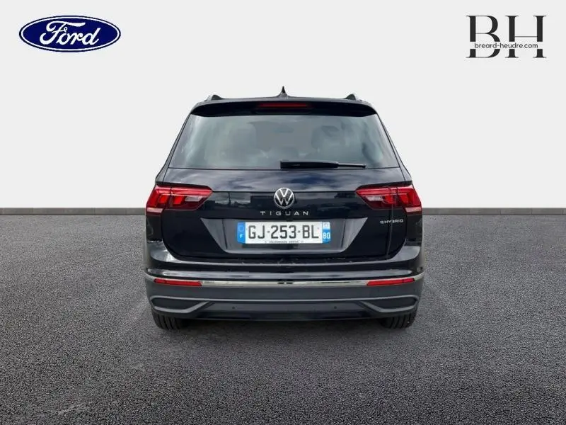 Vue arrière d’un Volkswagen Tiguan 1.4 eHybrid noir intense nacré, avec feux LED et logo central visible.