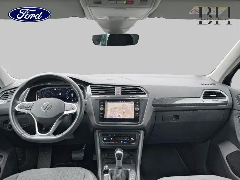 Vue intérieure avant du Volkswagen Tiguan 1.4 eHybrid 2022, tableau de bord noir avec écran tactile GPS et volant multifonction.