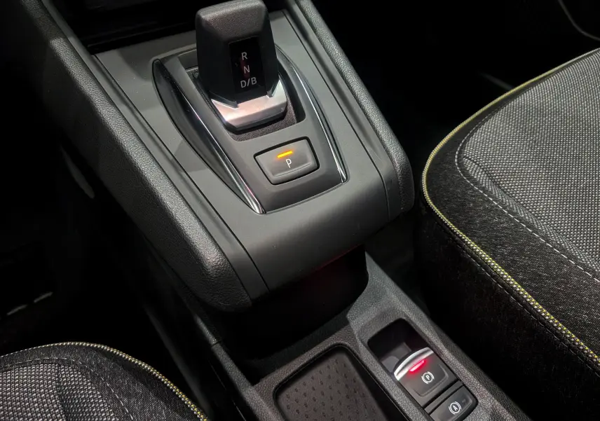 Gros plan sur la console centrale du Renault Captur hybride 2025, avec levier de vitesses automatique et sièges tissu noirs.