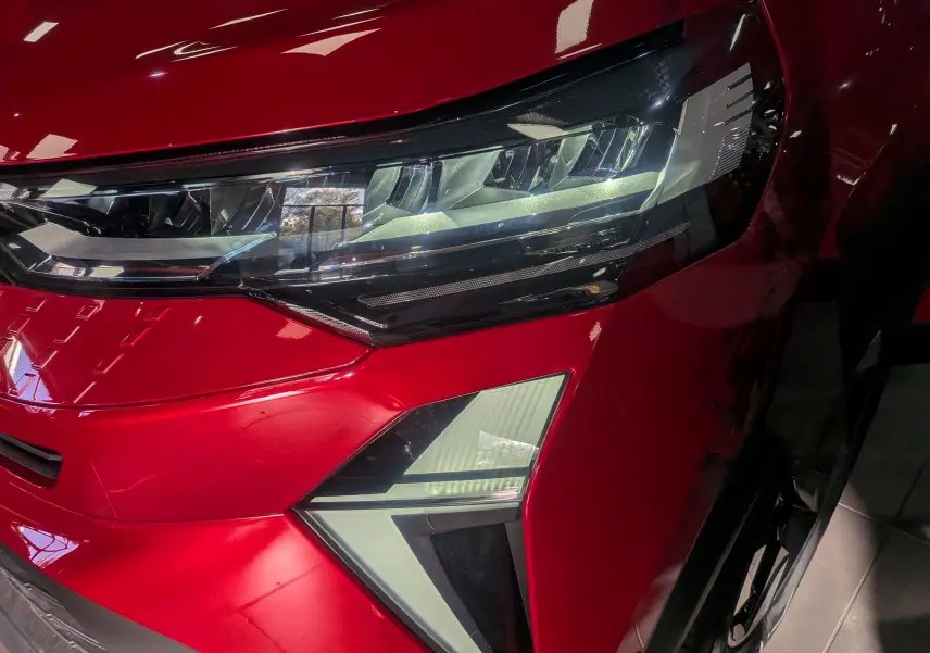 Gros plan sur le phare avant droit du Renault Captur E-TECH rouge Flamme avec toit noir, mettant en valeur son design LED moderne.