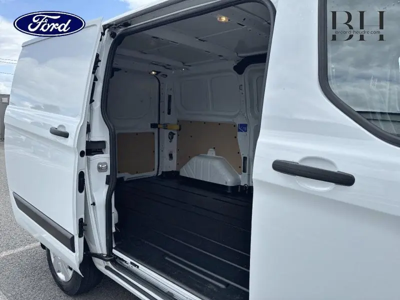 Vue latérale droite du Ford Transit Custom Fourgon blanc Glacier 2023 avec porte coulissante ouverte montrant l'espace de chargement vide.