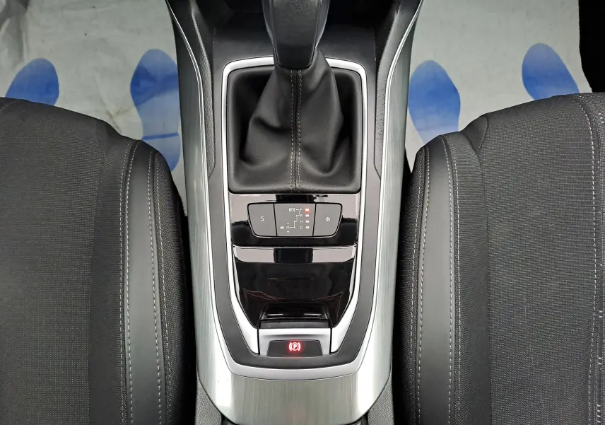 Vue plongeante sur la console centrale de la Peugeot 308 gris, avec levier de vitesse automatique et sièges noirs.